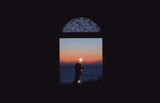 A serene scene of a hand holding a glowing star against a navy backdrop.