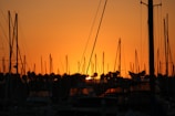 Close-up of a sailboat's mast silhouetted against a glowing golden horizon.