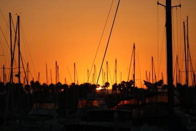 Close-up of a sailboat's mast silhouetted against a glowing golden horizon.