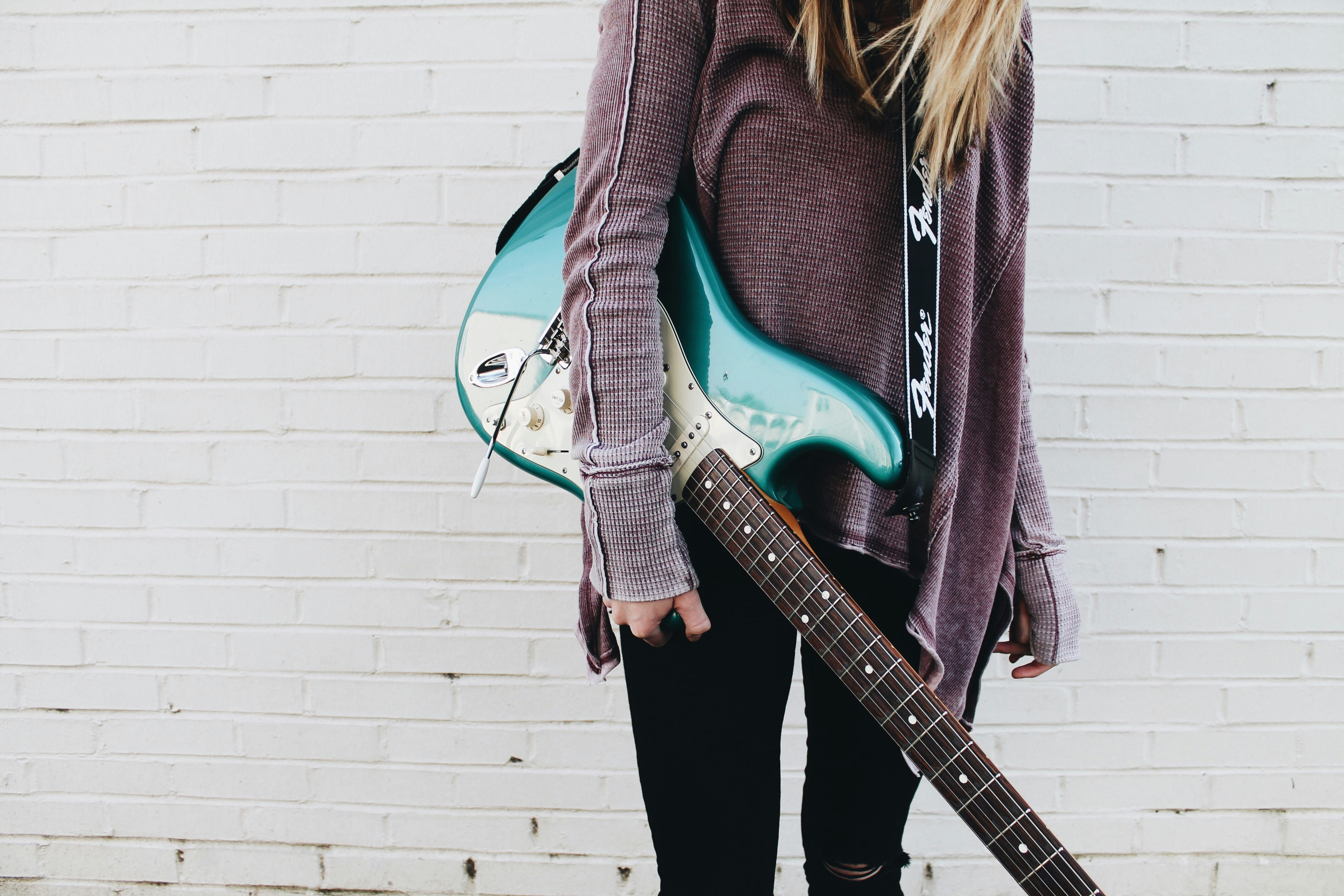 woman carrying green stratocaster guitar