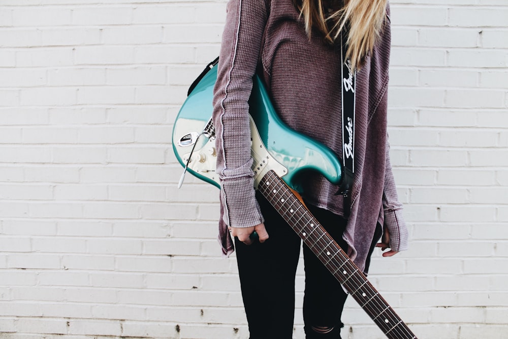 woman carrying green stratocaster guitar