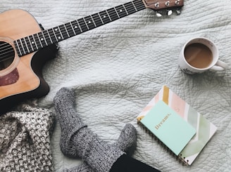 person wearing gray socks near acoustic guitar