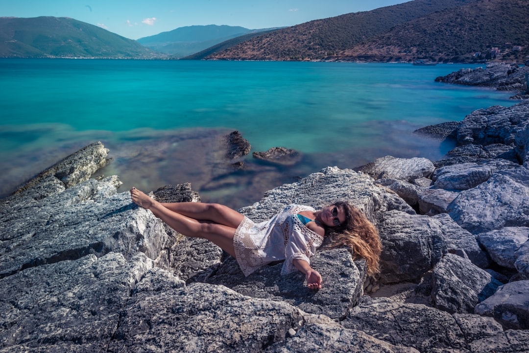 woman lying on gray rock near lake
