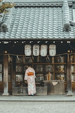 woman wearing orange and white kimono dress standing near the house
