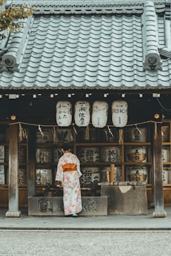woman wearing orange and white kimono dress standing near the house