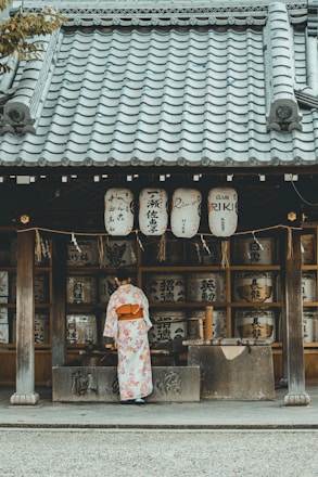 woman wearing orange and white kimono dress standing near the house