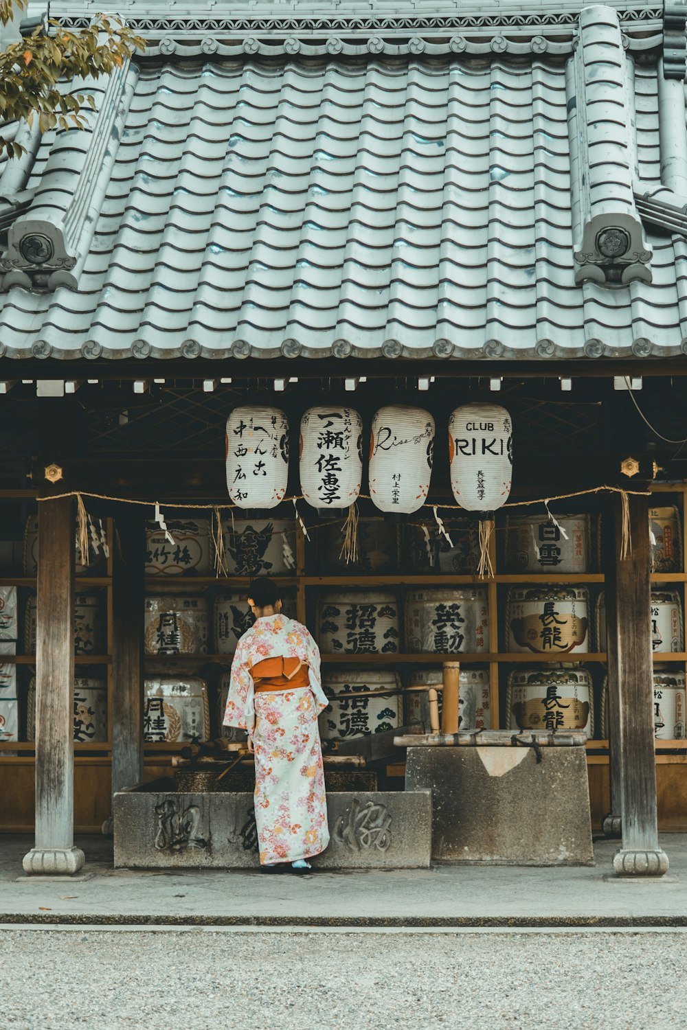 Mujer con vestido de kimono naranja y blanco de pie cerca de la casa