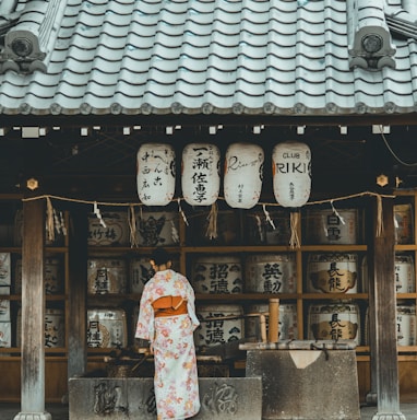 woman wearing orange and white kimono dress standing near the house