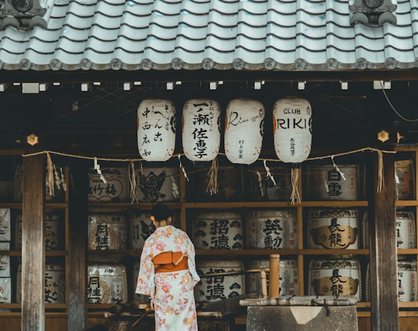 woman wearing orange and white kimono dress standing near the house