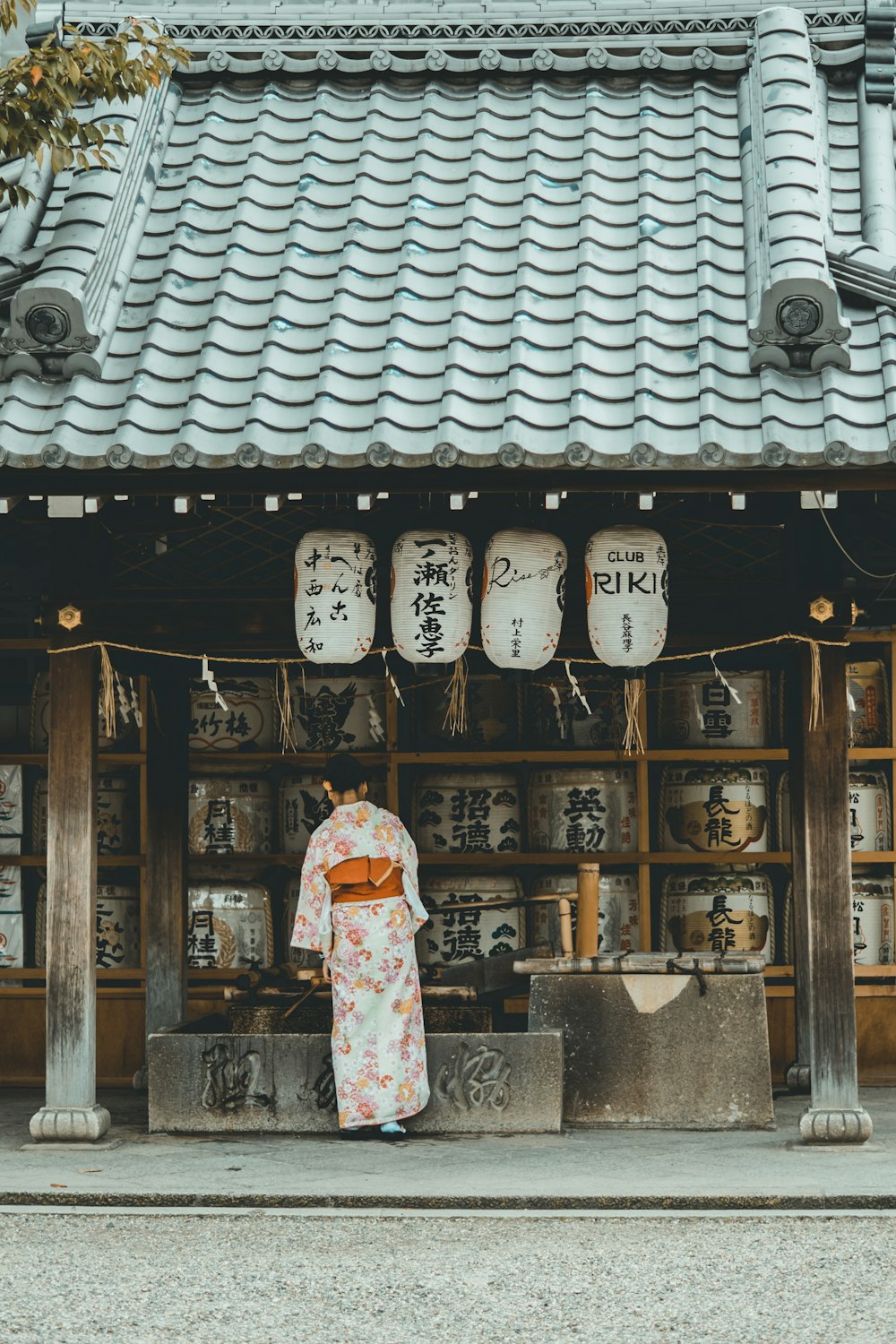 주황색과 흰색 기모노 드레스를 입은 여자가 집 근처에 서 있습니다.