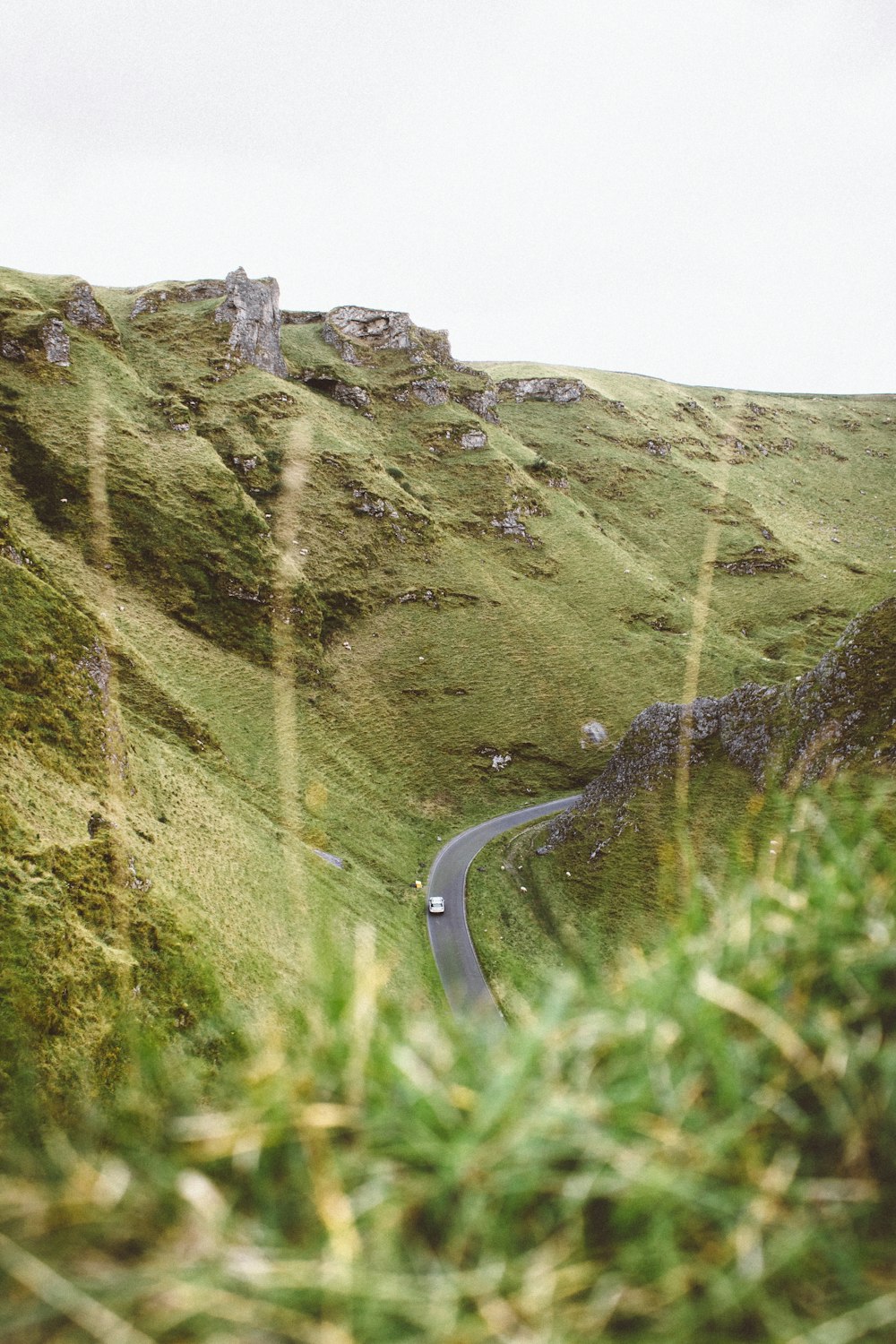Carretera de hormigón gris entre montañas cubiertas de hierba