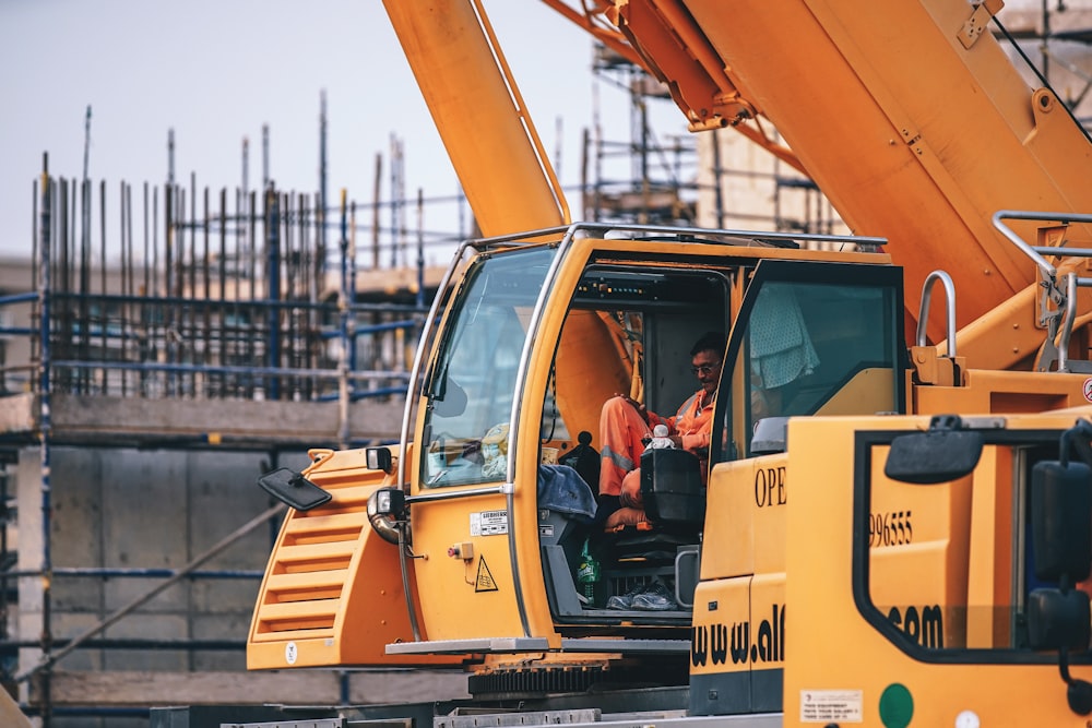 man riding orange heavy equipment at daytime