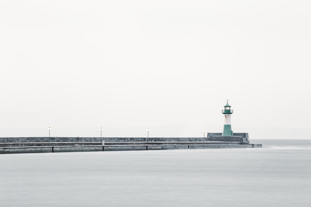 white and green lighthouse near body of water