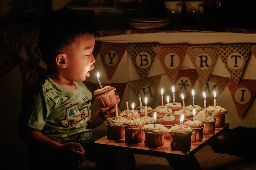 ろうそくを吹くカップケーキを持つ少年