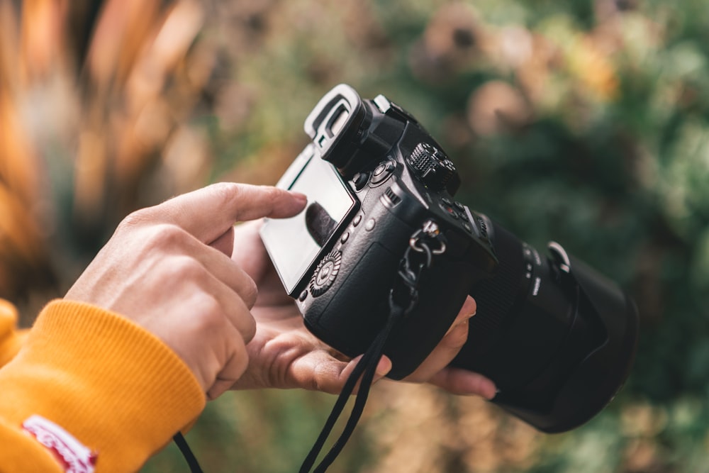 person holding black DSLR camera