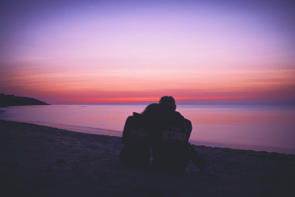 man and woman hugging each other on seashore during sunset