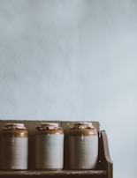 Handcrafted ceramic jars with botanical illustrations, holding fragrant balms.