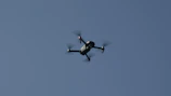 Close-up of drone propellers spinning mid-flight against a clear blue sky.
