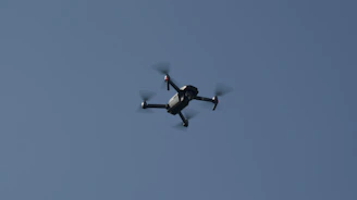 Close-up of drone propellers spinning rapidly against a clear blue sky.