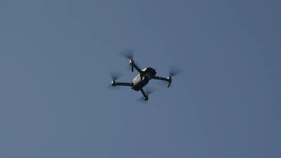 Close-up of a drone’s propellers spinning against a baby blue sky.