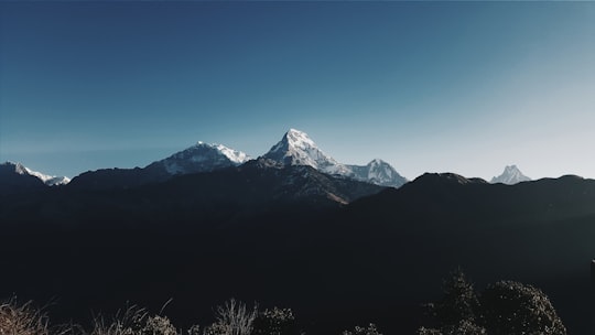 silhouette of mountain with view of snow-capped mountain range during daytime photo in Annapurna Nepal