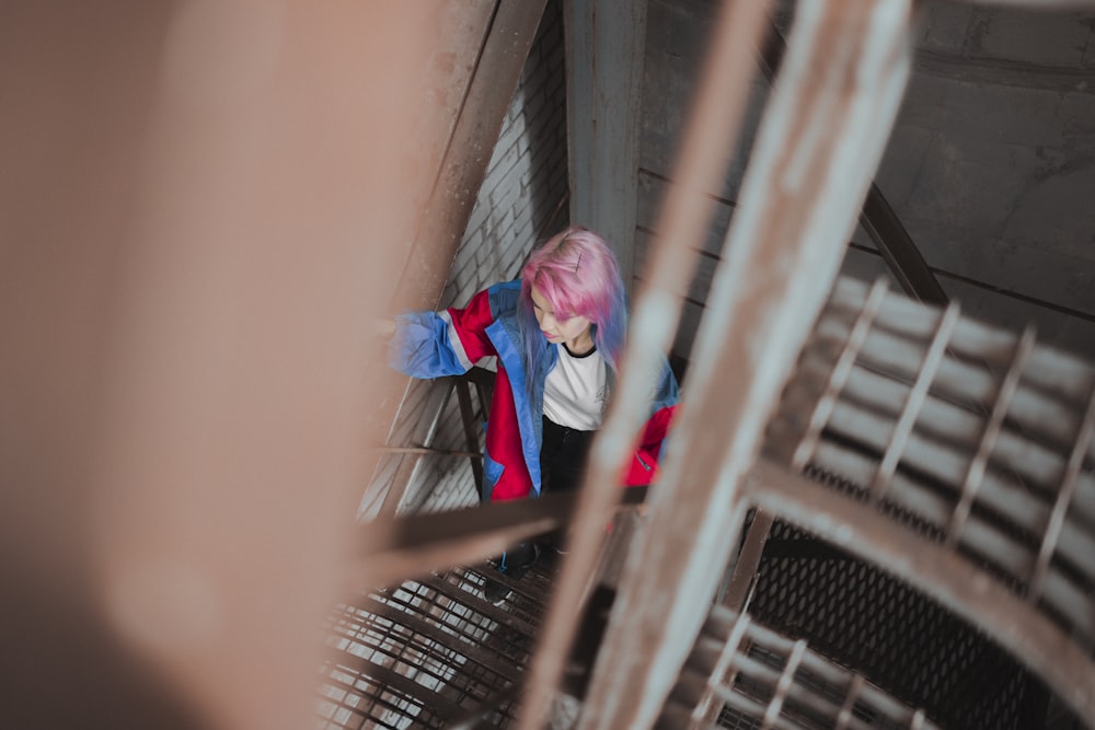 selective-focus photography of woman climbing metal stairs during daytime