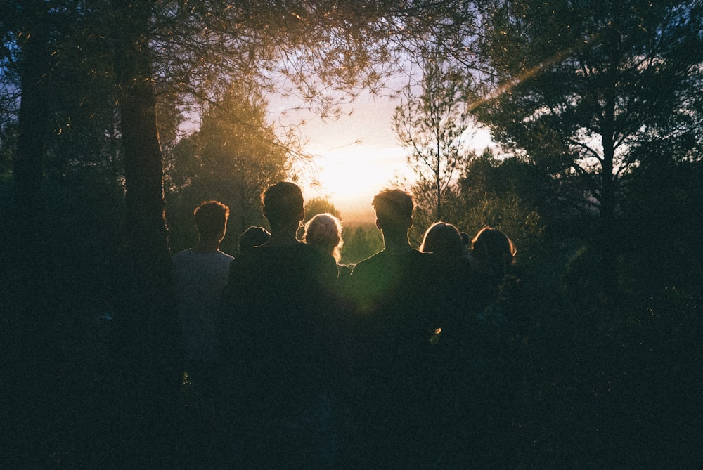 several people watching the sunrise in the middle of forest