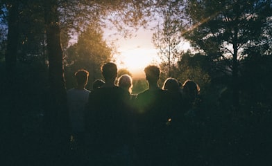 several people watching the sunrise in the middle of forest