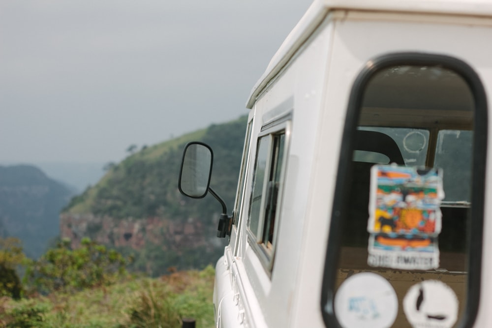 white vehicle facing green grass mountains