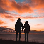 silhouette photo of man and woman on cliff