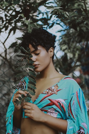 woman holding leaf beside tree