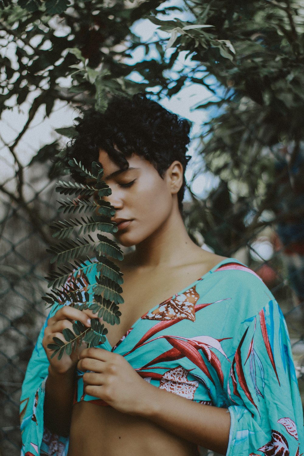 woman holding leaf beside tree