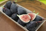 A mix of walnuts and figs displayed on a minimalist wooden tray.