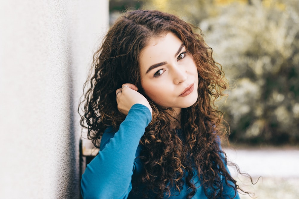 tilt-shift lens photography of woman sitting near wall during daytime