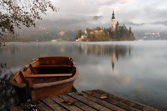 A peaceful lakeside view with a wooden dock and a small boat under soft morning light