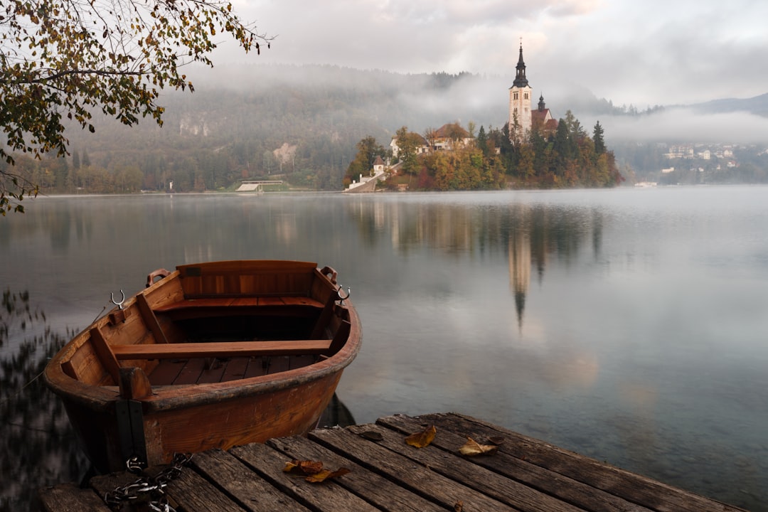 Early morning at Lake Bled brown wooden boat floating on body of water