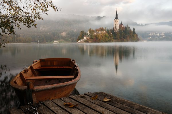 A wooden boat at a dock on misty Lake Bled in Slovenia