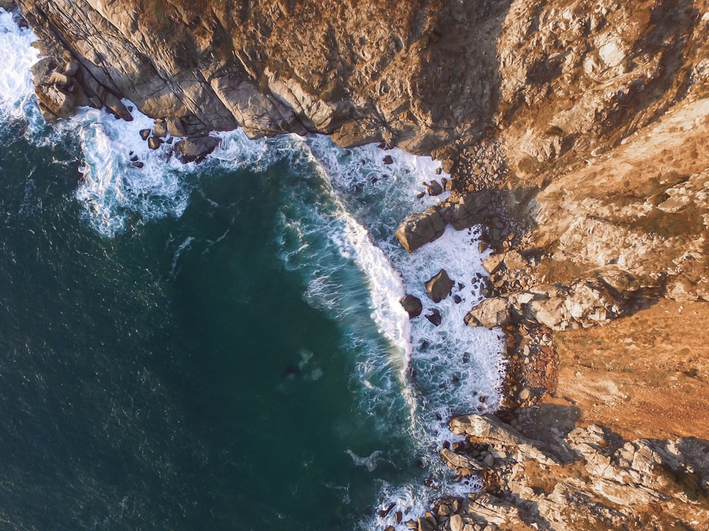 high angle photo of beach waves near mountain slope