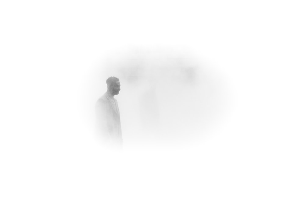 Un uomo in piedi in una zona nebbiosa con le spalle alla telecamera
