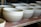 Close-up of handcrafted ceramic bowls stacked on a wooden shelf in soft natural light.