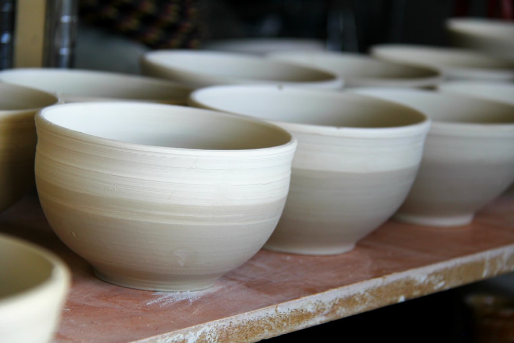 white-and-grey clay pots on brown wooden plank