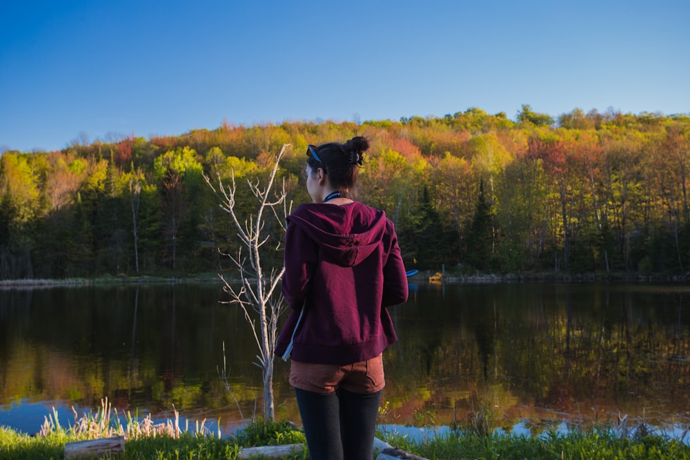 woman wearing red hoodie while standing near lake