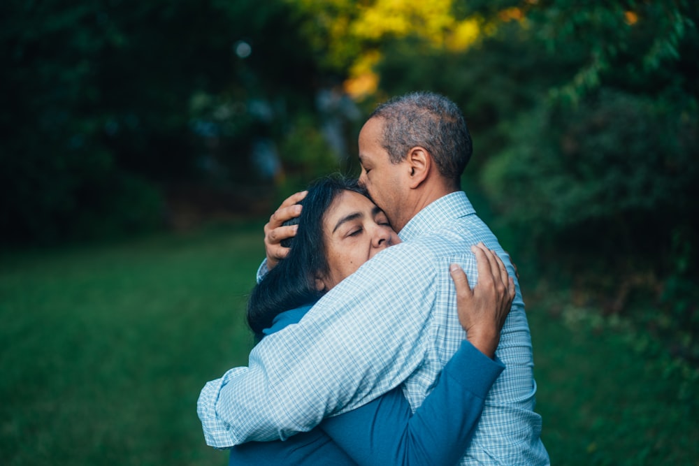 man hugging woman near trees