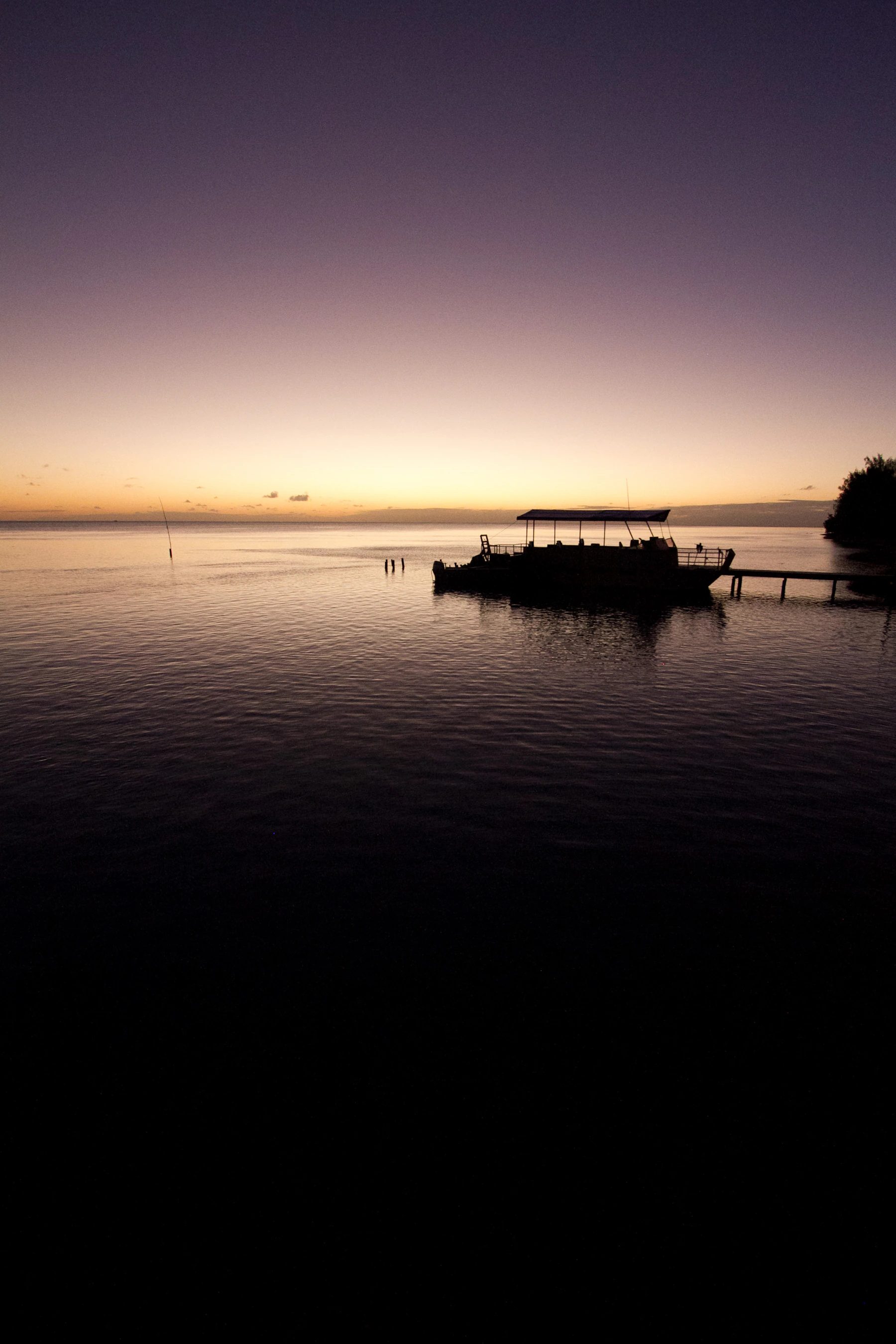 Boat resting on the glassy Aitutaki Lagoon at sunset
