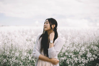 Woman in a white knit cardigan standing in a field of white blossoms