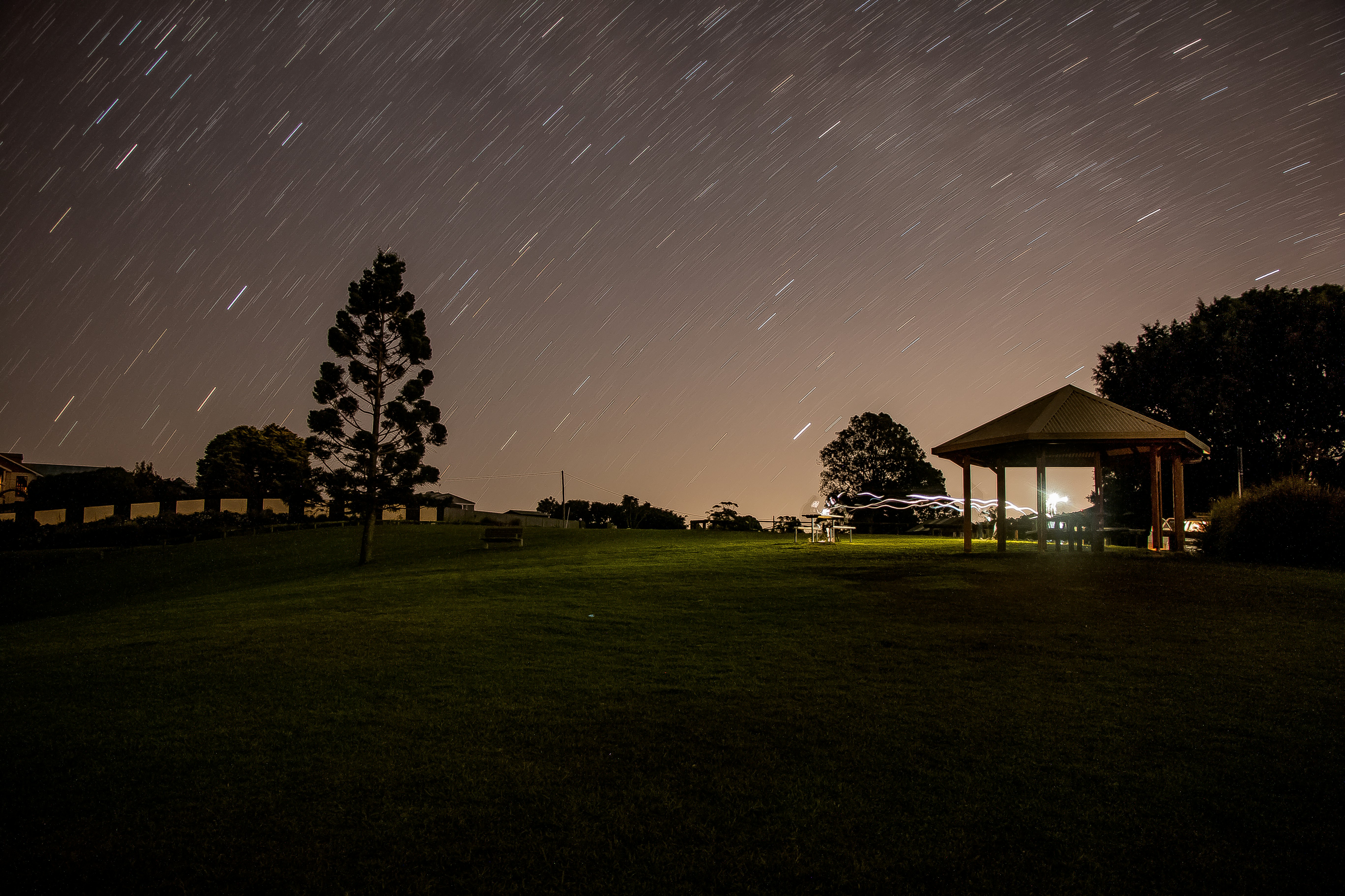 brown gazebo under starry night in time lapse photography