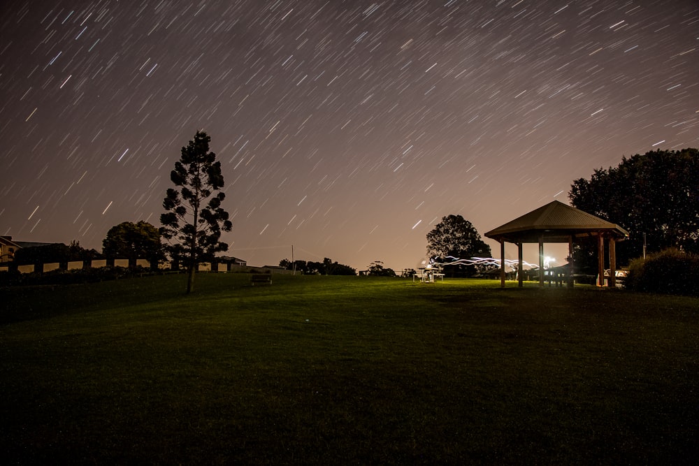 brown gazebo under starry night in time lapse photography