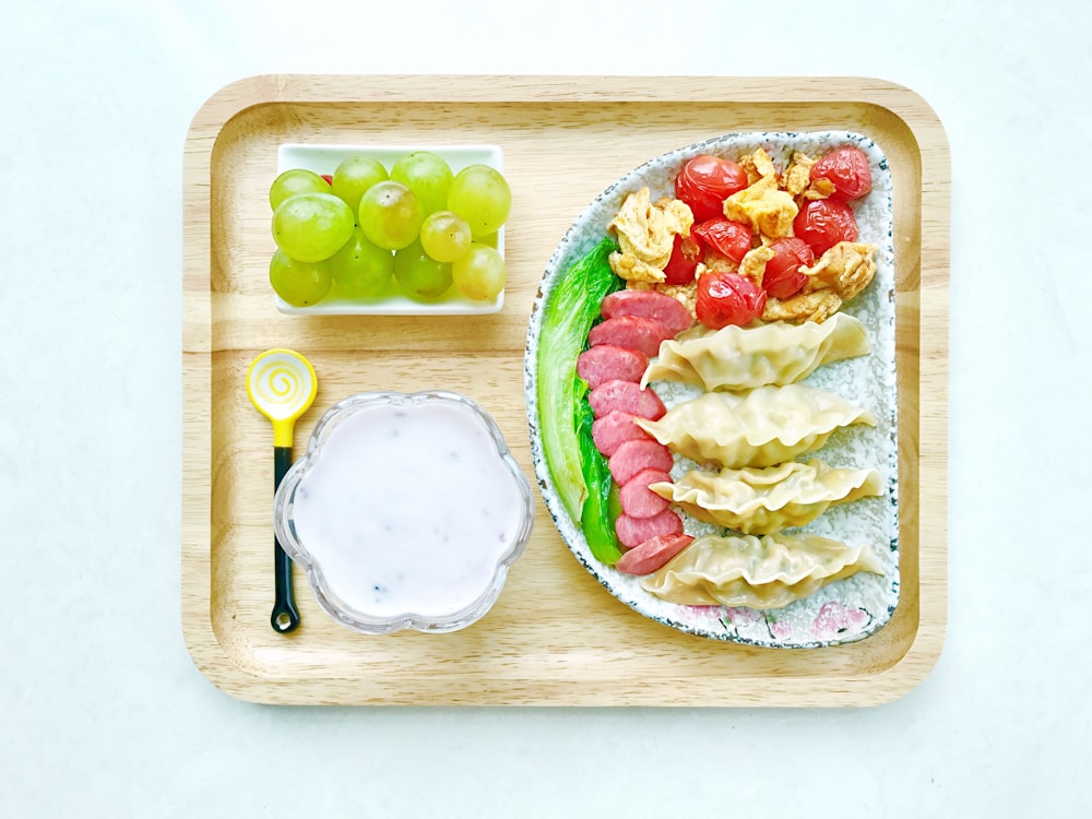 Comida en platos de cerámica en bandeja cuadrada de madera