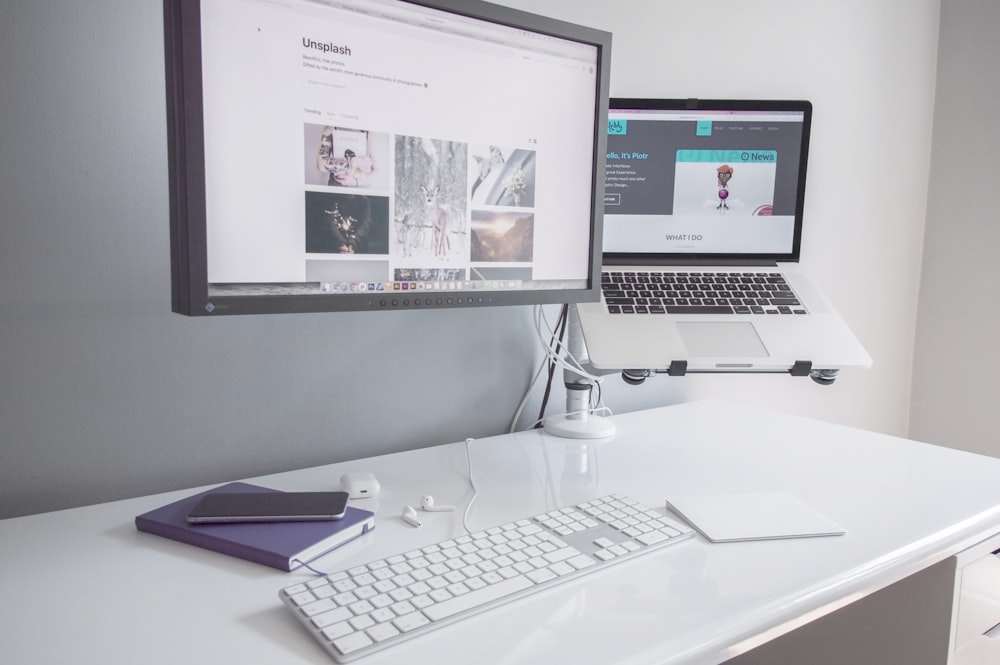 moniteur à écran plat tourné près du MacBook Air allumé sur une table en bois blanc