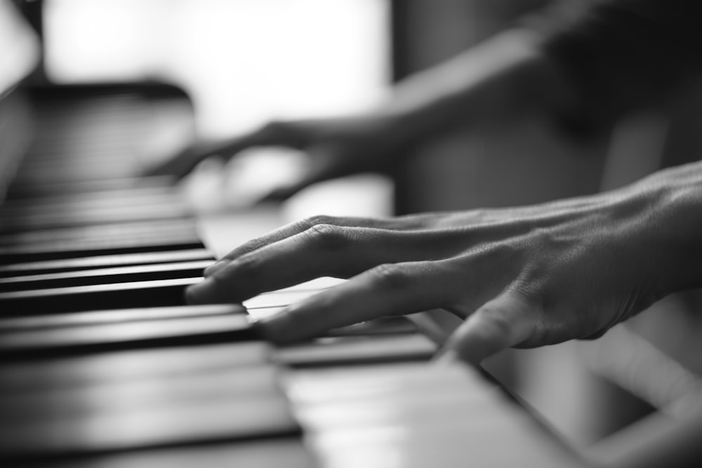 greyscale photo of person playing piano